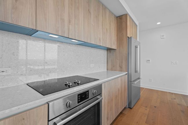 Kitchen featuring stainless steel appliances, modern cabinets, light brown cabinetry, light wood-type flooring, and recessed lighting | Image 8