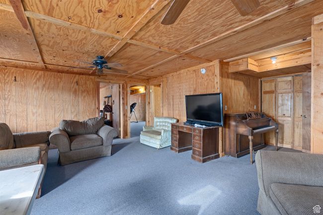 Living room featuring carpet flooring, ceiling fan, wooden walls, and wood ceiling | Image 13