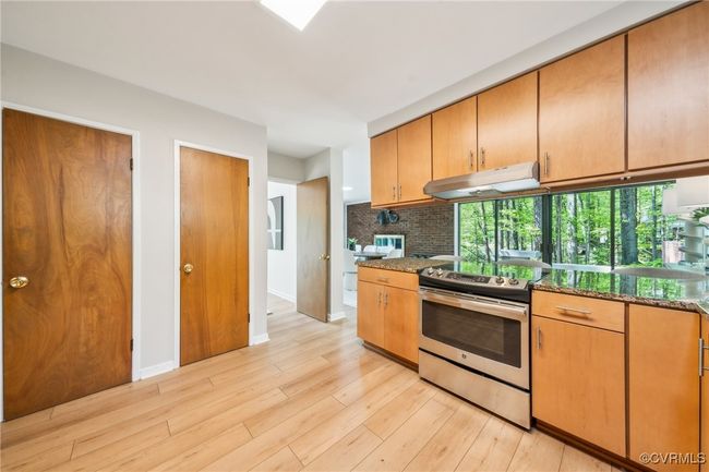 Kitchen featuring tasteful backsplash, stainless steel electric range, light wood-style flooring, baseboards, and under cabinet range hood | Image 27