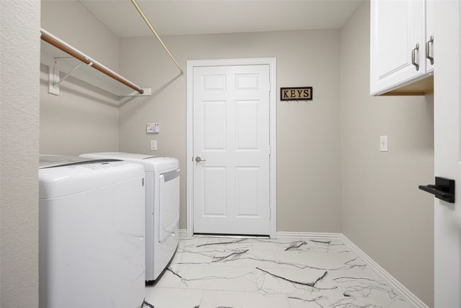 Spacious laundry room featuring cabinet space, light marble finish floors, and direct access to garage. | Image 24