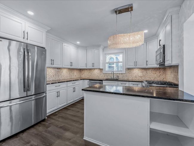Kitchen with stainless steel appliances, a sink, white cabinets, and recessed lighting | Image 6