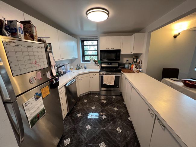 Kitchen with white cabinets, stainless steel appliances, light countertops, and a sink | Image 4