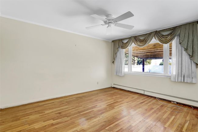 Spare room with ornamental molding, a ceiling fan, light wood-style floors, baseboards, and baseboard heating | Image 14