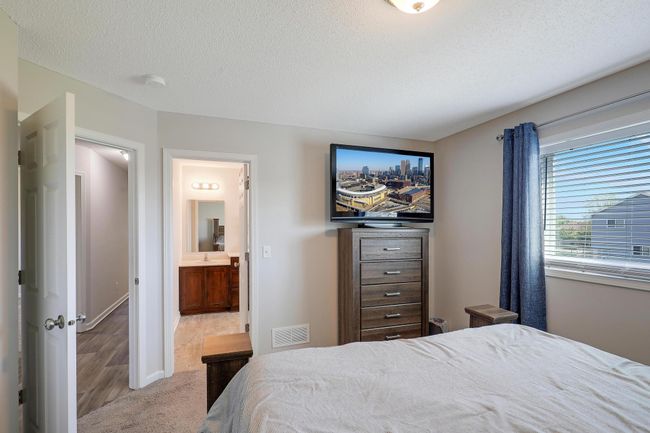 This spacious primary bedroom features a private en suite bath, offering a serene retreat with convenience and comfort. | Image 18
