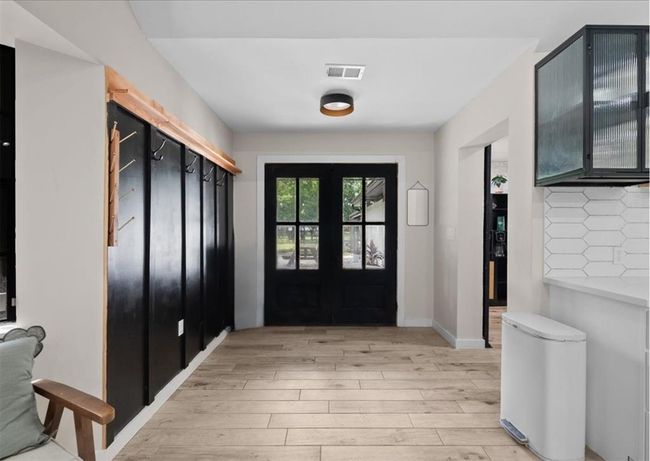 Welcoming double-doors leading to the pool with bold black accents and functional wall-mounted hooks. | Image 23