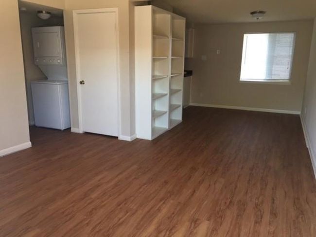 Unfurnished bedroom with stacked washer and clothes dryer, baseboards, and wood finished floors | Image 8
