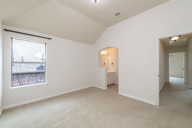 Empty room with attic access, light colored carpet, lofted ceiling, and arched walkways | Image 30