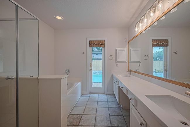 Enjoy a separate jetted soaking tub, updated standalone shower, upgraded quartz countertops, and all-new sinks, faucets, and vanity lights—plus the convenience of a private door leading to the backyard. | Image 19