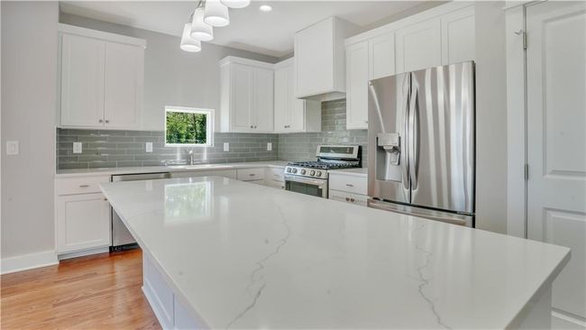 Kitchen featuring appliances with stainless steel finishes, a sink, white cabinets, and decorative backsplash | Image 6