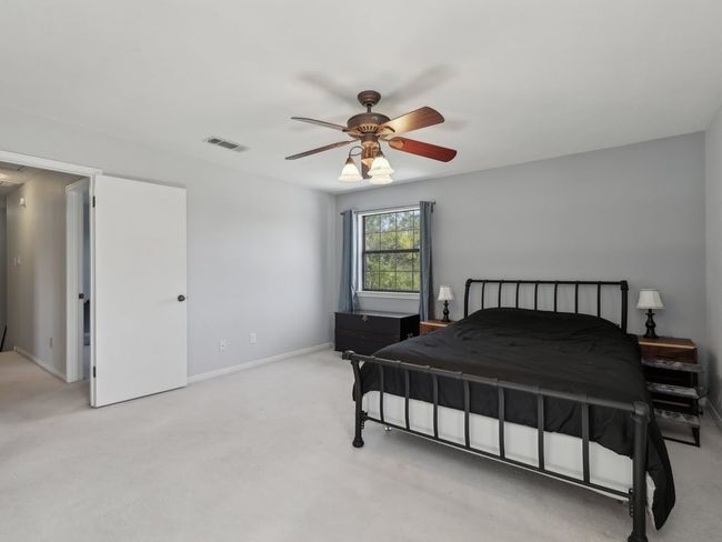 Bedroom featuring visible vents, baseboards, light colored carpet, and ceiling fan | Image 23