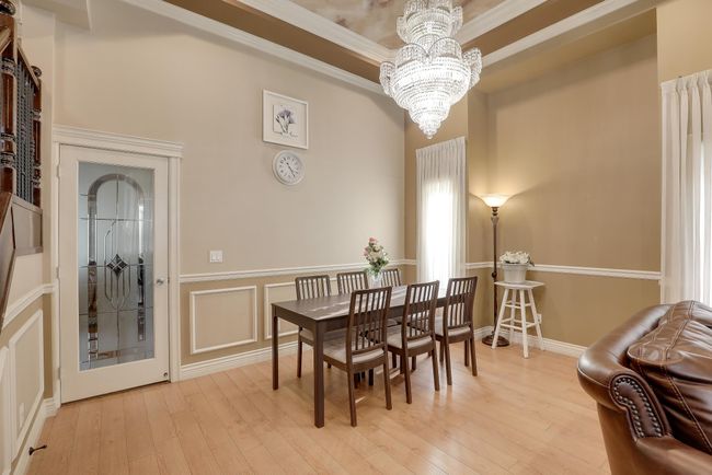 Dining space with light wood finished floors, ornamental molding, a wainscoted wall, and a notable chandelier | Image 12