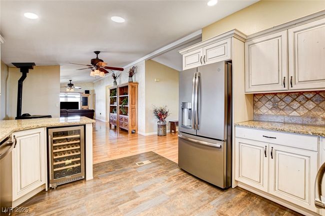Kitchen featuring wine cooler, stainless steel appliances, a ceiling fan, light wood-style flooring, and tasteful backsplash | Image 23