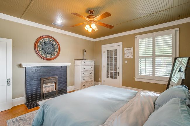 Bedroom featuring wood finished floors, crown molding, a brick fireplace, and a ceiling fan | Image 37