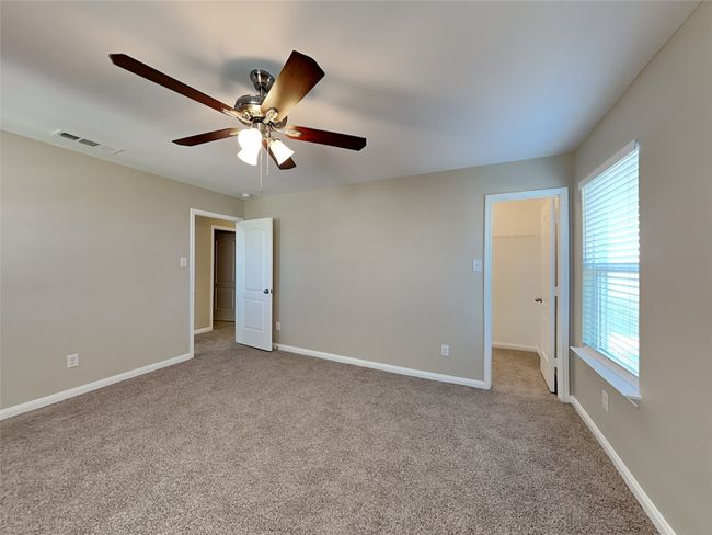 Unfurnished bedroom featuring multiple windows, a spacious closet, carpet flooring, and a ceiling fan | Image 14