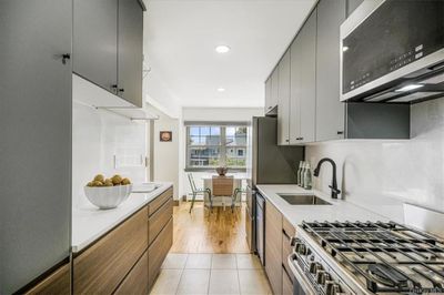 This unit's showstopper - A brand new kitchen featuring quartz countertop & backsplash, modern 2-tone cabinetry, open shelving, and stainless steel appliances. | Image 1