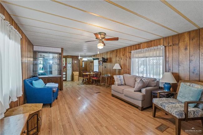 Living area with wood walls, light wood-style flooring, a ceiling fan, and a textured ceiling | Image 4