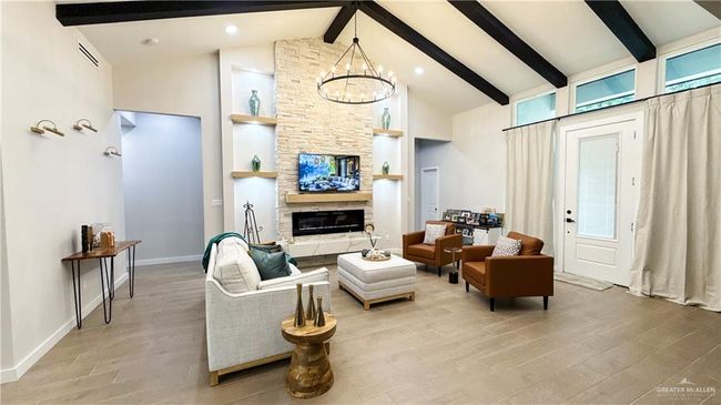 Living room featuring high vaulted ceiling, beam ceiling, light wood-style flooring, a chandelier, and a fireplace | Image 6