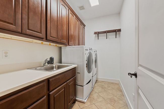 Laundry area with washer and clothes dryer, cabinet space, and light tile patterned floors | Image 36