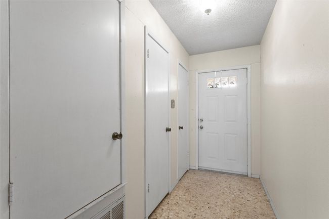 Entryway with a textured ceiling and dark speckled floor | Image 36