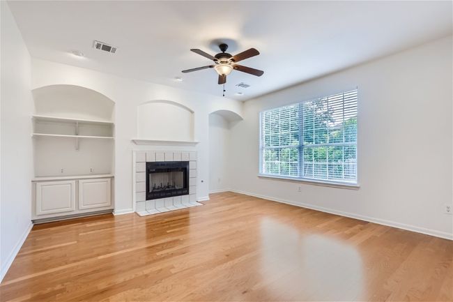 Unfurnished living room with a tiled fireplace, light wood-type flooring, a ceiling fan, and baseboards | Image 14