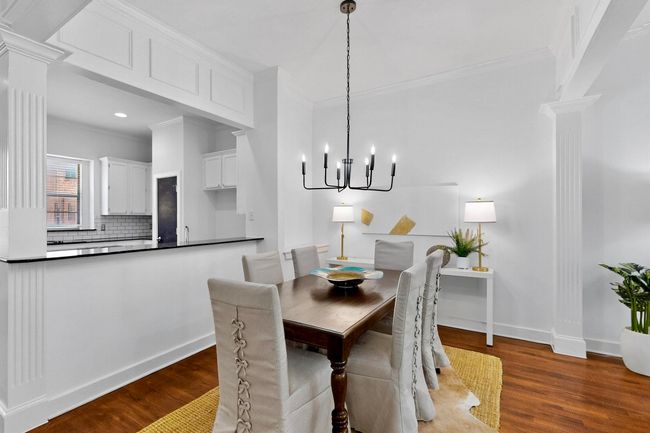 Dining space with ornate columns, wood finished floors, a chandelier, and ornamental molding | Image 15