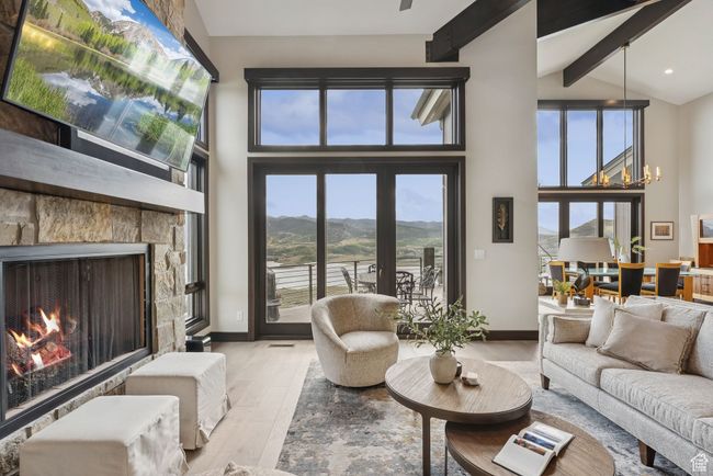 Living room with wood finished floors, beam ceiling, high vaulted ceiling, a stone fireplace, and a chandelier | Image 13