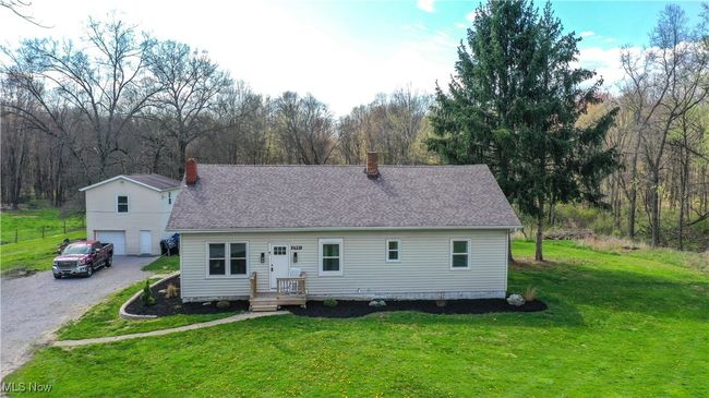 View of front of house featuring a chimney, a shingled roof, gravel driveway, a front yard, and an attached garage | Image 37