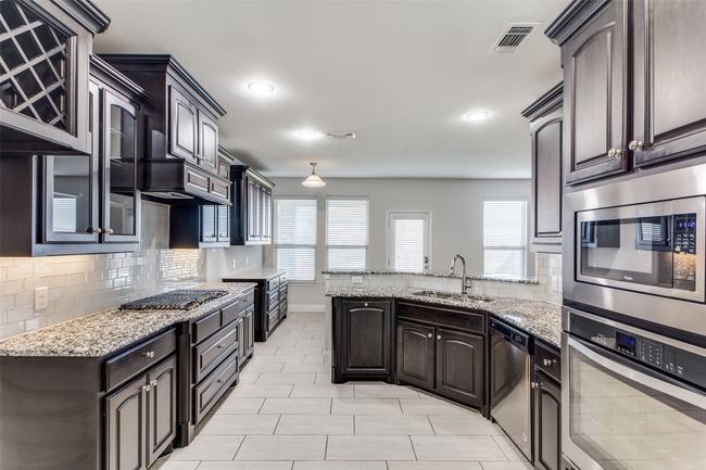 Kitchen with backsplash, sink, stainless steel appliances, and dark brown cabinets | Image 12