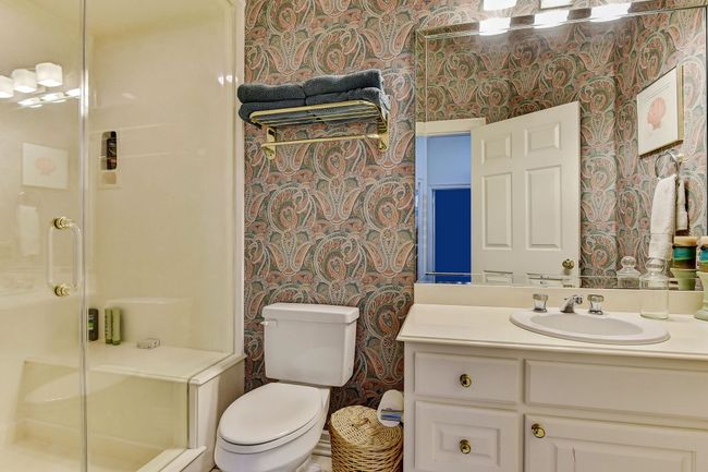 Full bathroom featuring wallpapered walls, vanity, toilet, and a stall shower | Image 25