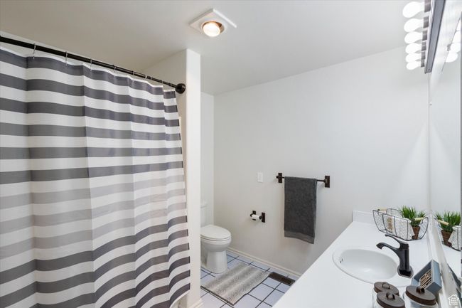 Bathroom featuring a shower with curtain, toilet, vanity, and tile patterned flooring | Image 21
