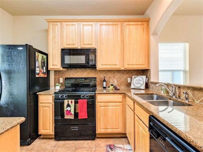 The kitchen comes ready to use with all appliances included, granite countertops, tile backsplash, and pantry storage. | Image 12