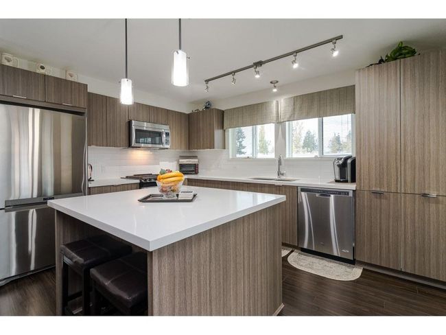 Kitchen featuring modern cabinets, appliances with stainless steel finishes, a sink, and light countertops | Image 8