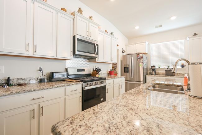 Kitchen with light stone countertops, visible vents, a sink, stainless steel appliances, and white cabinetry | Image 6