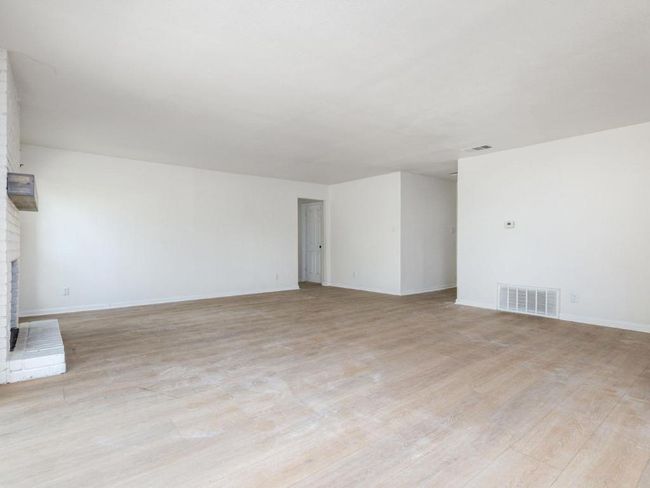 Unfurnished living room with light wood-type flooring, a brick fireplace, and baseboards | Image 15