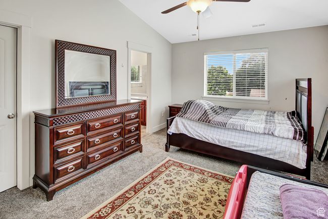 Bedroom with light colored carpet, vaulted ceiling, a ceiling fan, and connected bathroom | Image 19