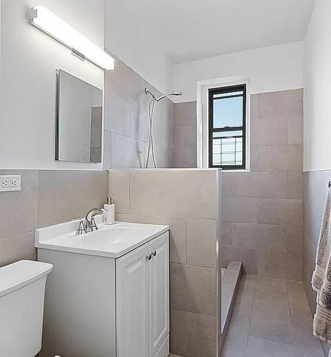 Full bathroom with tile walls, tiled shower, vanity, and toilet | Image 4