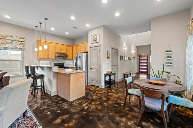 Kitchen featuring freestanding refrigerator, a peninsula, under cabinet range hood, decorative backsplash, and light brown cabinets | Image 5