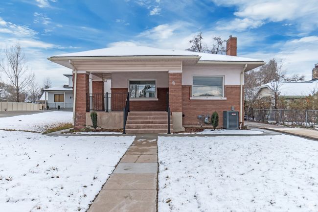 Snow covered property featuring brick siding, central air condition unit, a chimney, and fence | Image 24