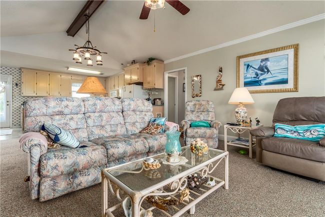 Living area featuring a ceiling fan, vaulted ceiling with beams, and ornamental molding | Image 35