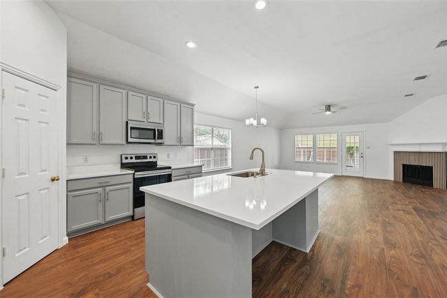 Kitchen with gray cabinets, stainless steel appliances, a sink, vaulted ceiling, and open floor plan | Image 12