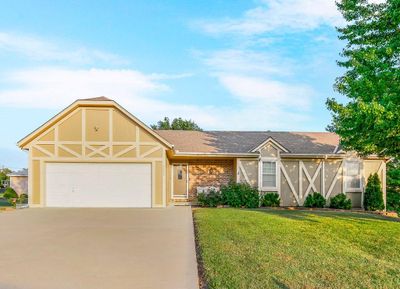 English style home featuring a front yard and a garage | Image 1