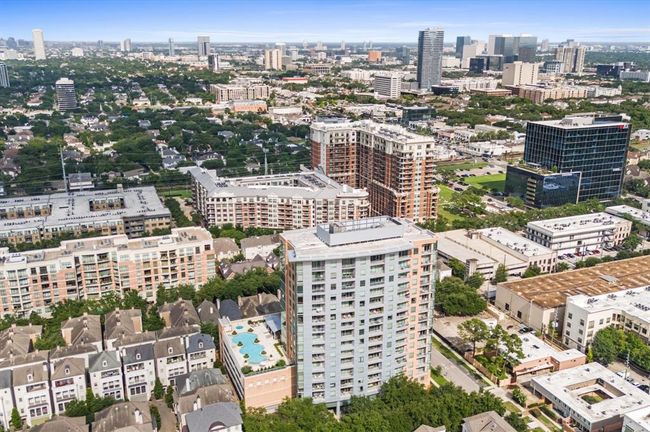This aerial photo showcases a vibrant urban area with a mix of high-rise buildings and residential complexes. The neighborhood is lush with greenery, offering a combination of modern living and natural surroundings. The view includes a swimming pool and proximity toRiver Oaks District, ideal for a convenient lifestyle. | Image 31