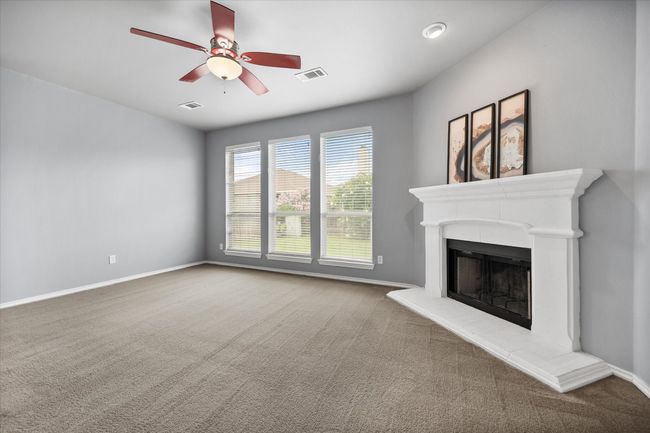 Unfurnished living room featuring carpet flooring, ceiling fan, and a fireplace with raised hearth | Image 12