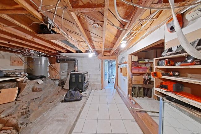 Unfinished basement (lower level) under height. Storage room/ utility room with hot water tank and woodstove with water heater bladder. | Image 70