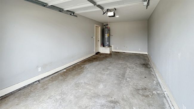 Garage featuring electric water heater and a garage door opener | Image 14