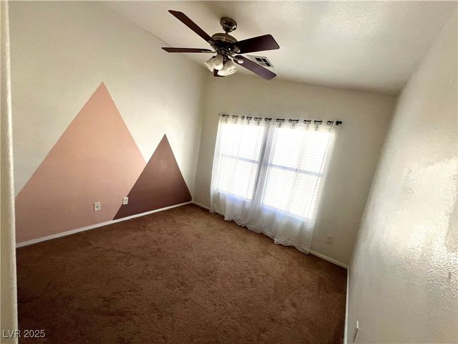 Carpeted empty room with baseboards, ceiling fan, visible vents, and vaulted ceiling | Image 15