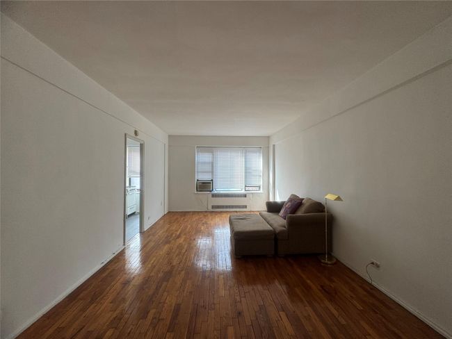 Living area featuring dark wood-style flooring, radiator heating unit, and cooling unit | Image 4