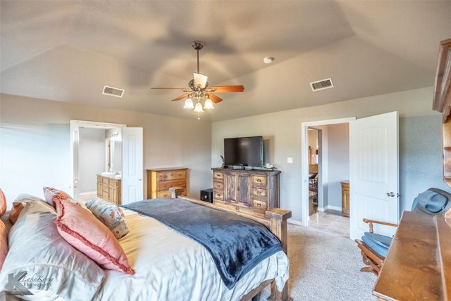 Bedroom featuring light carpet, vaulted ceiling, baseboards, a ceiling fan, and connected bathroom | Image 14