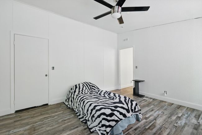 Bedroom featuring wood finished floors, visible vents, baseboards, and ceiling fan | Image 10