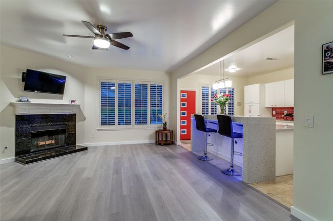 Living room featuring wood finished floors, a ceiling fan, a fireplace, and baseboards | Image 9